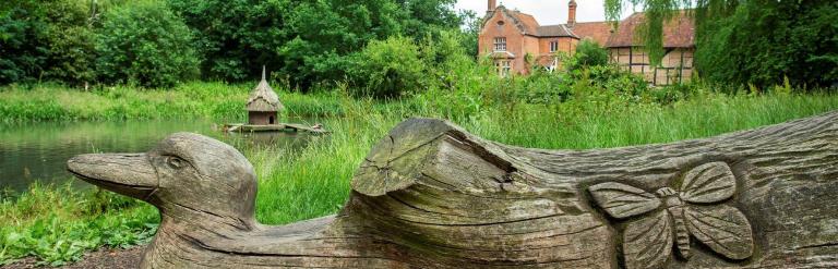 Log carved to look like a duck near pond in Hartley Wintney