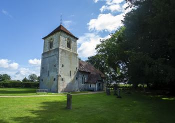 Church in Winchfield with blue sky behind surrounded by green grass and the churchyard