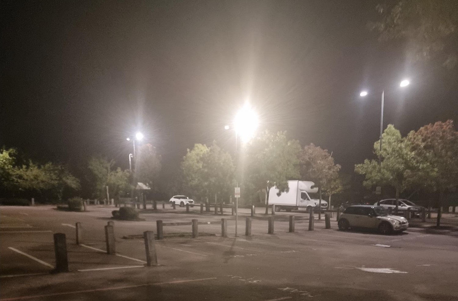 LED street lights in dark car park with cars in the background