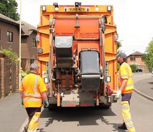 Two men in orange high vis collecting black wheelie bins with an orange bin collection lorry