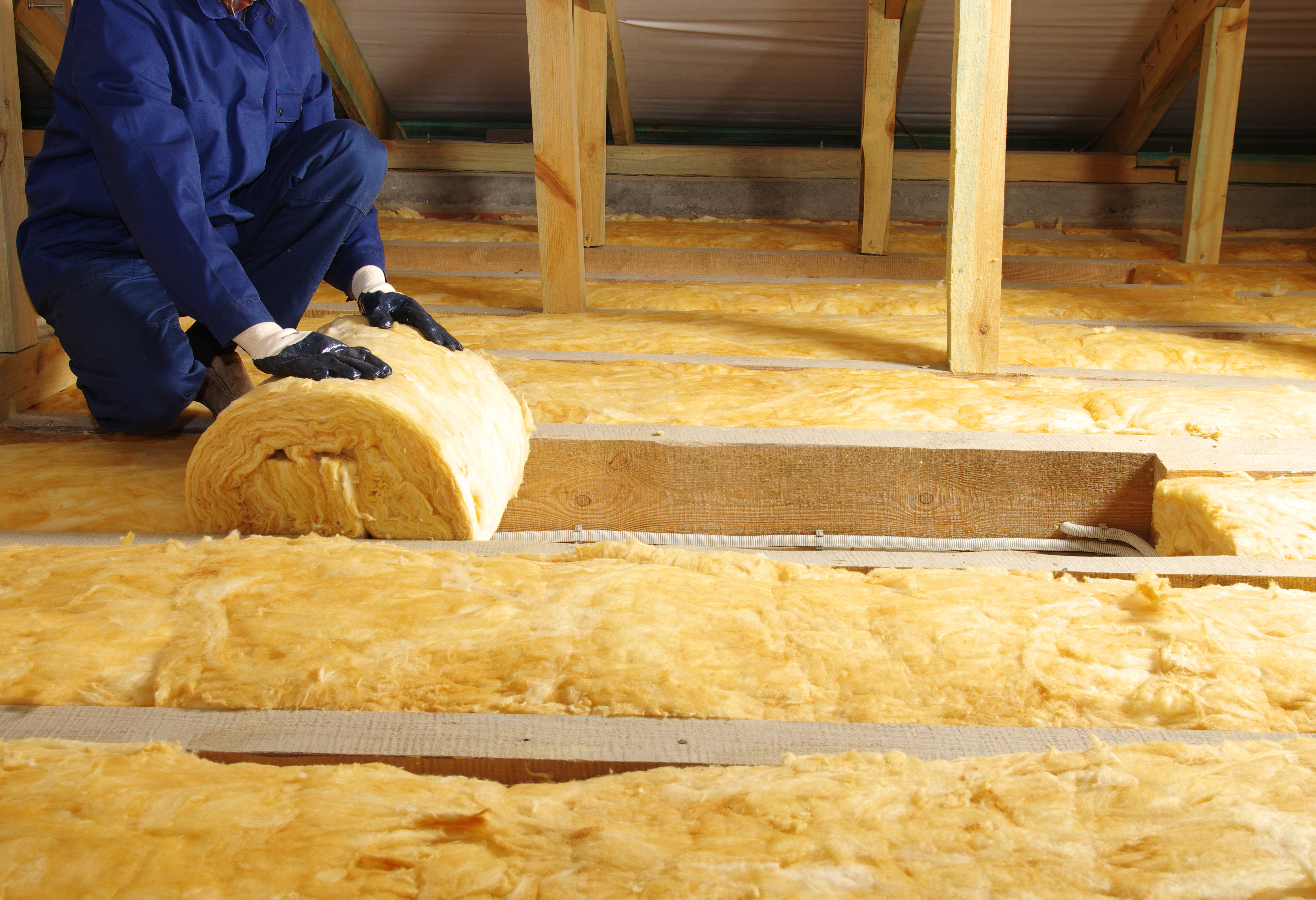 Person rolling out loft insulation