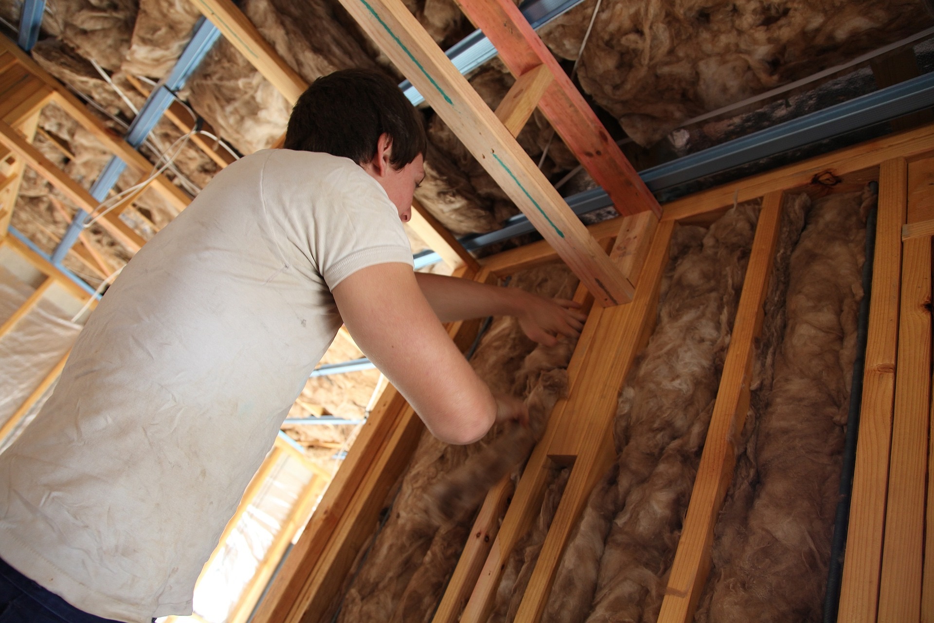 Man fitting insulation in his roof