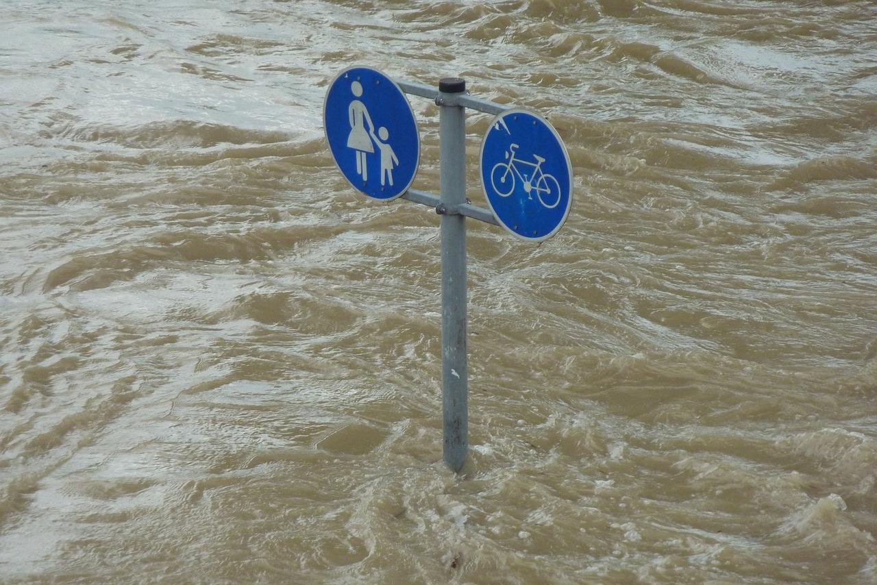 Flood waters swirling round two road signs.