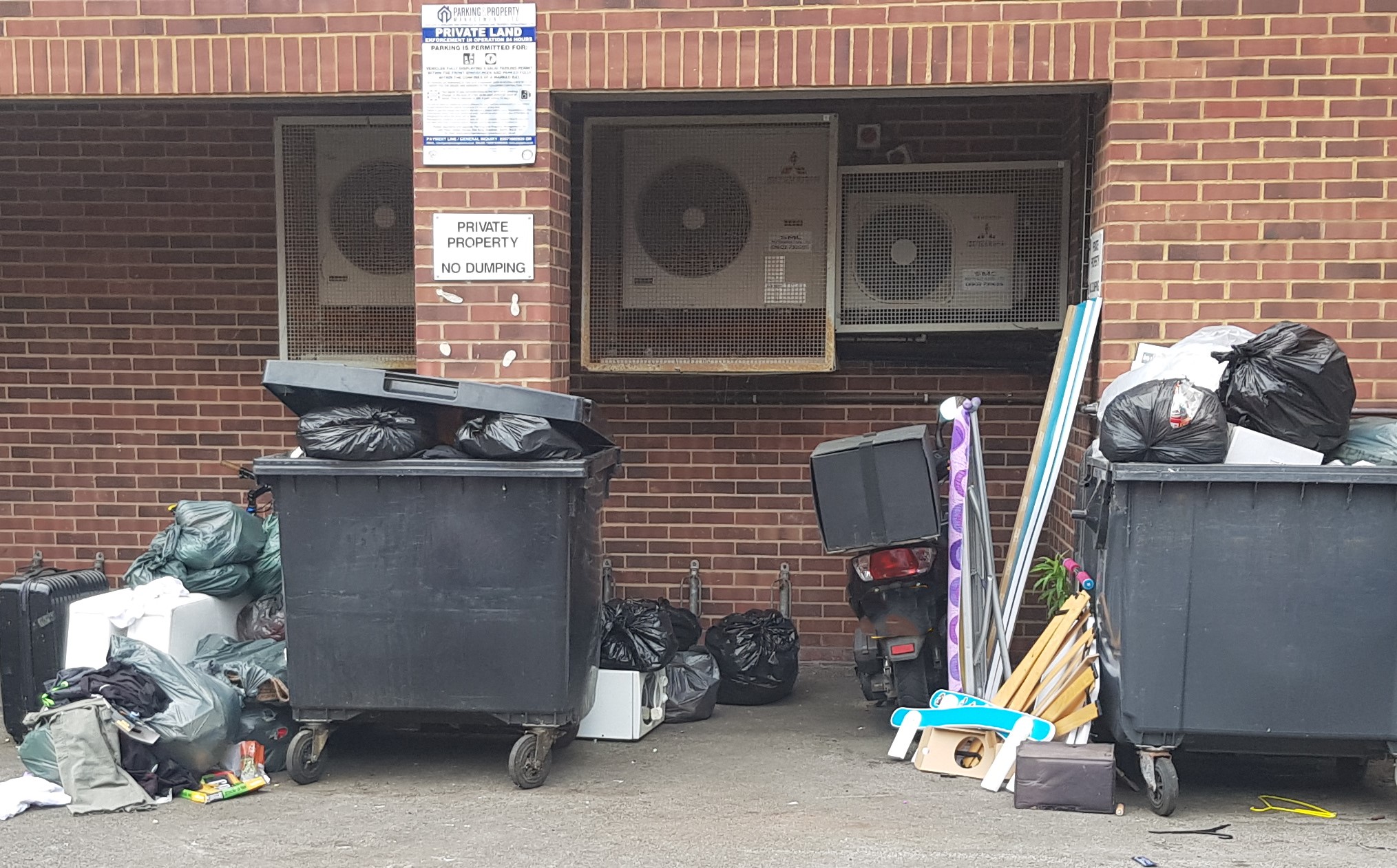 Fly-tipped rubbish by industrial bins 