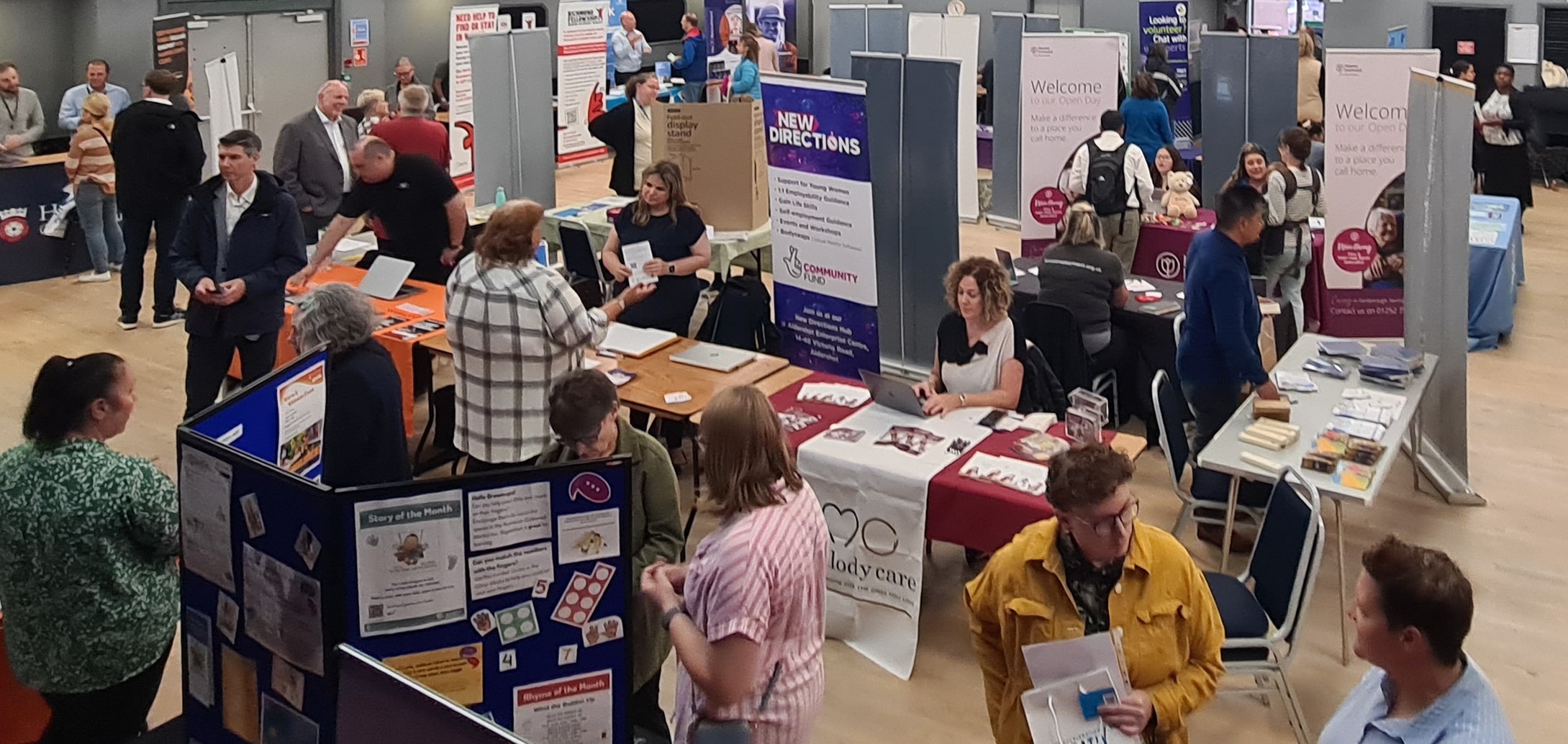 A hall with groups of people talking to each other with stands and posters