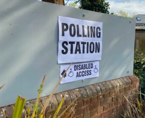 Polling station sign on a white background with disabled access sign underneath