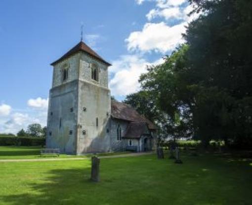 Church in Winchfield with blue sky behind surrounded by green grass and the churchyard