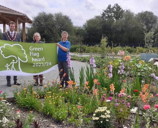 Leader of the Council Councillor David Neighbour, Hart District Council Chairman Councillor Peter Wildsmith, Hart Voluntary Action Wellbeing Projects Officer Amanda Slater and Hart Countryside Ranger Sarah Leedham at Edenbrook Country Park with the Green Flag Award flag
