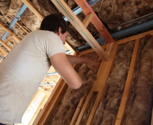 Man fitting insulation in his roof