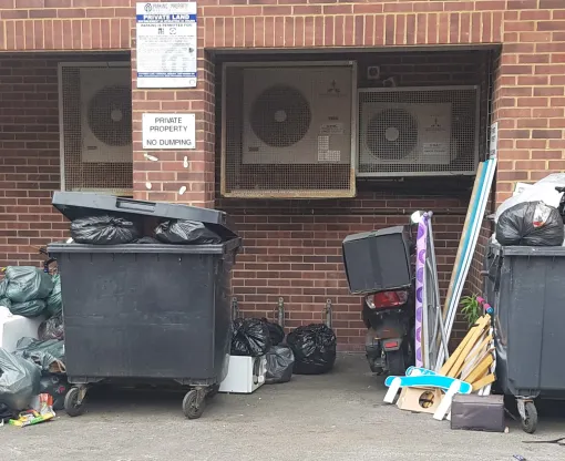 Fly-tipped rubbish by industrial bins 