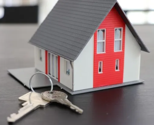 Model of a house with a house key on a house ring