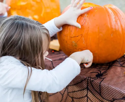 A child carving an orange pumpkin