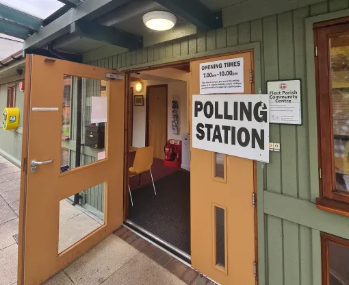 Open door into a polling station with polling station sign