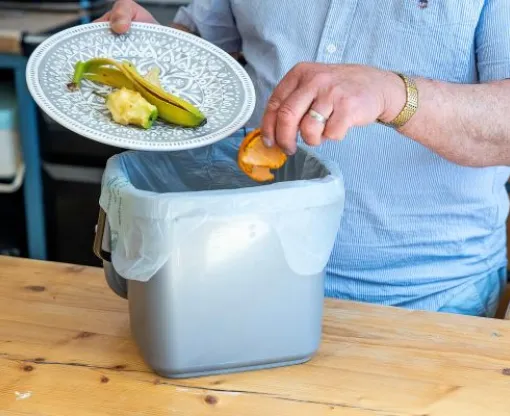 Person putting fruit peels in their food waste caddy