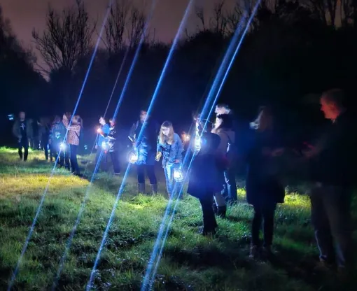 A group of families gather with torches at a bat walk event