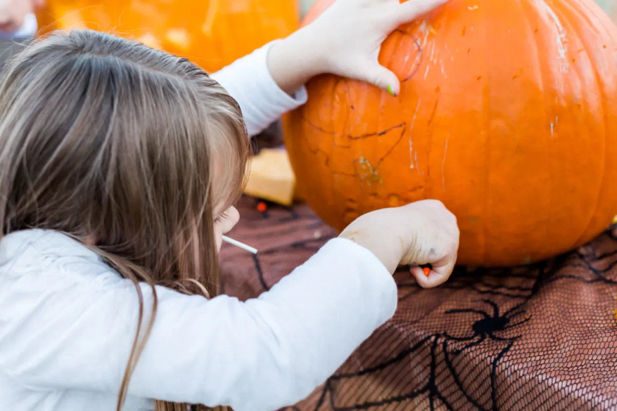 A child carving an orange pumpkin