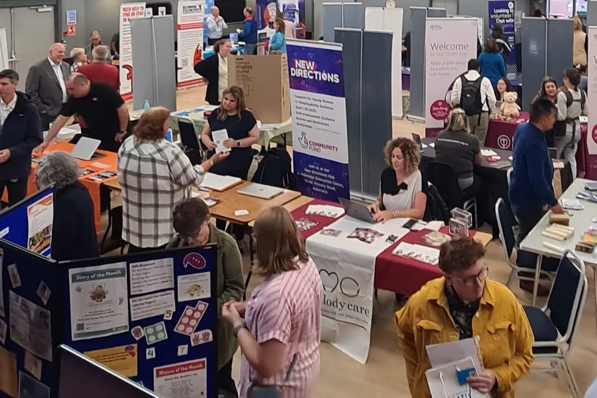 A hall with groups of people talking to each other with stands and posters