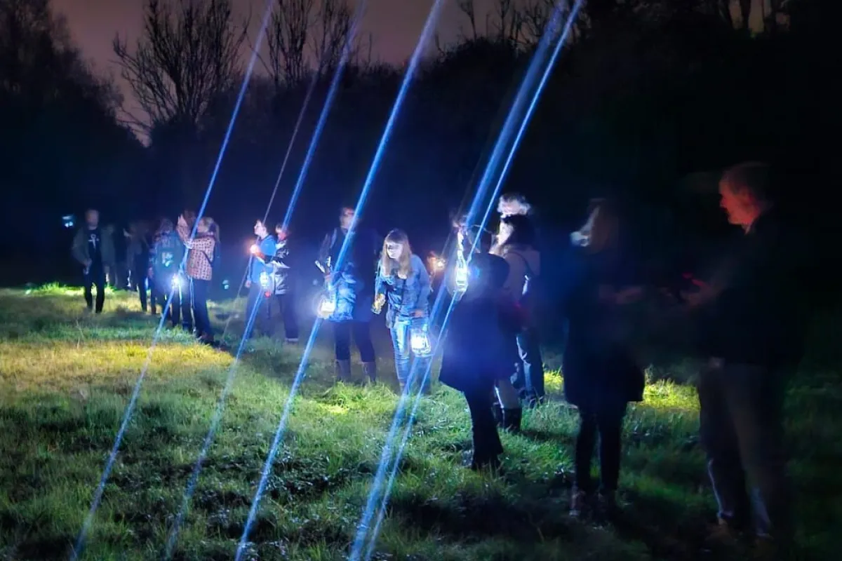 A group of families gather with torches at a bat walk event