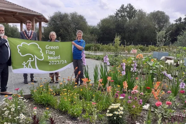 Leader of the Council Councillor David Neighbour, Hart District Council Chairman Councillor Peter Wildsmith, Hart Voluntary Action Wellbeing Projects Officer Amanda Slater and Hart Countryside Ranger Sarah Leedham at Edenbrook Country Park with the Green Flag Award flag
