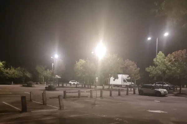 LED street lights in dark car park with cars in the background