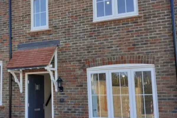 Front view of a red-bricked house with a open blue front door