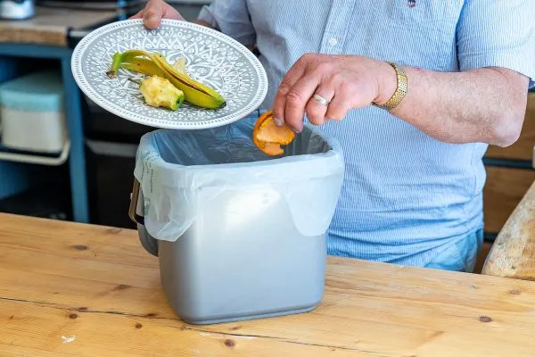 Person putting fruit peels in their food waste caddy