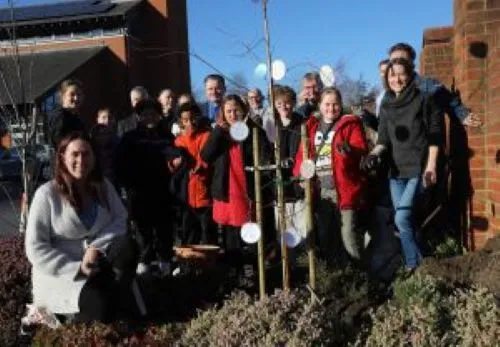 People standing by tree that has been planted outside Church on the Heath