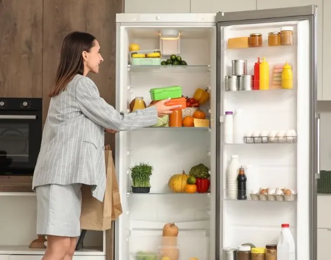 Lady putting food into fridge and looking at contents