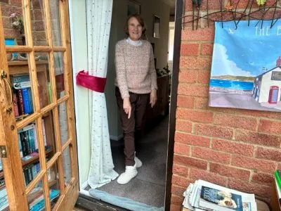 Lady standing by her conservatory and lounge door pointing at a draught excluder on the floor